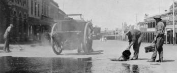 black and white photo of men pouring water on road