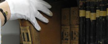 photo of person's hand pulling a book off shelf